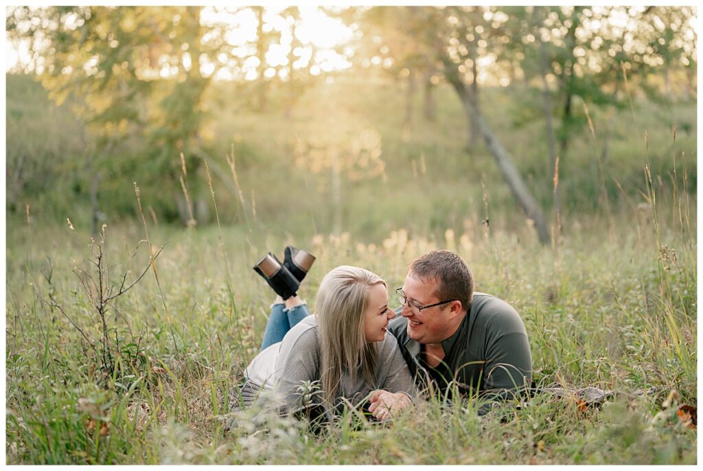 couple lays on ground smiling at each other at one of My Favorite Central Minnesota Engagement Session Locations