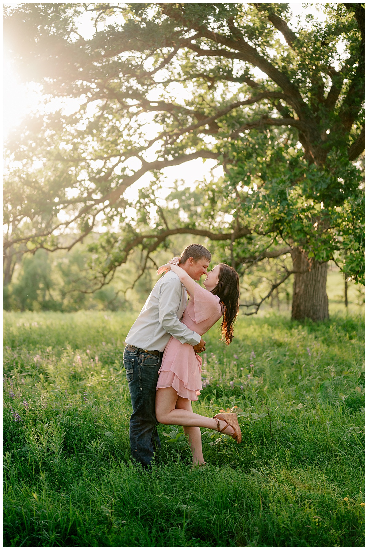 couple leans in for a kiss in a meadow during golden hour by Minnesota wedding photographer