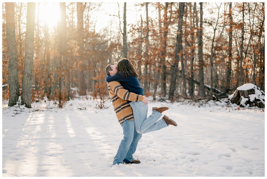man lifts woman and kisses her during Crosslake Nature Trail Winter Engagement 