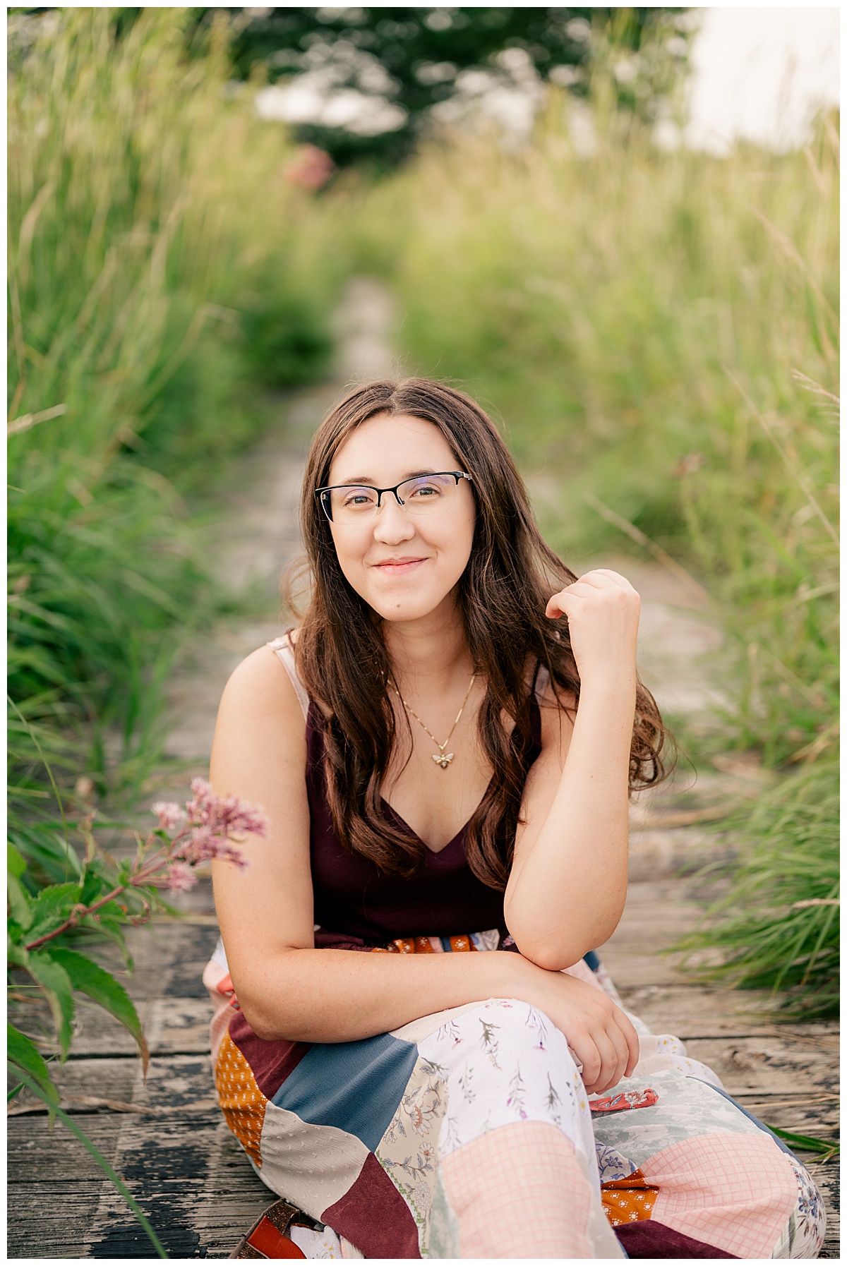 girl smiles while sitting on path through grass for summer mini sessions