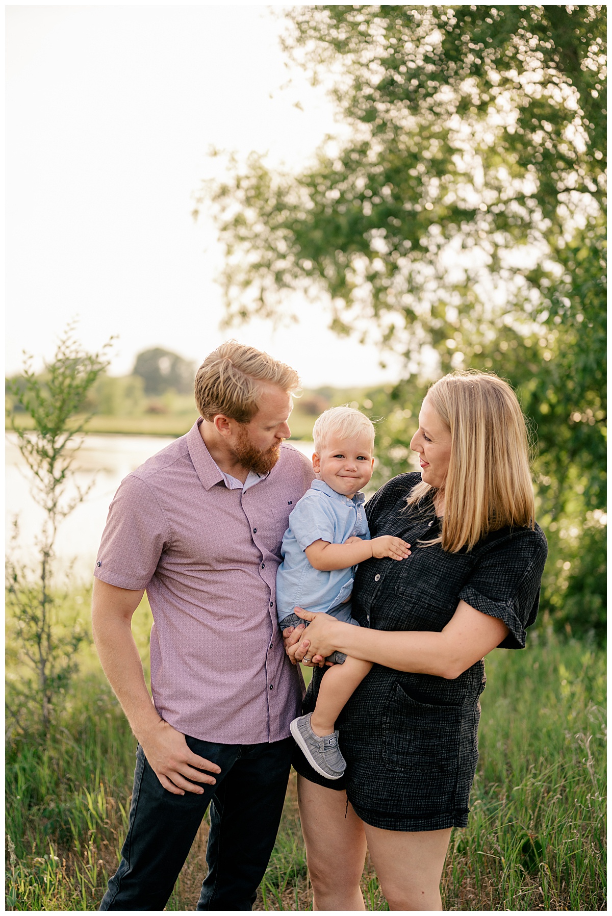 toddler held by his mom as dad looks at them by Minnesota photographer
