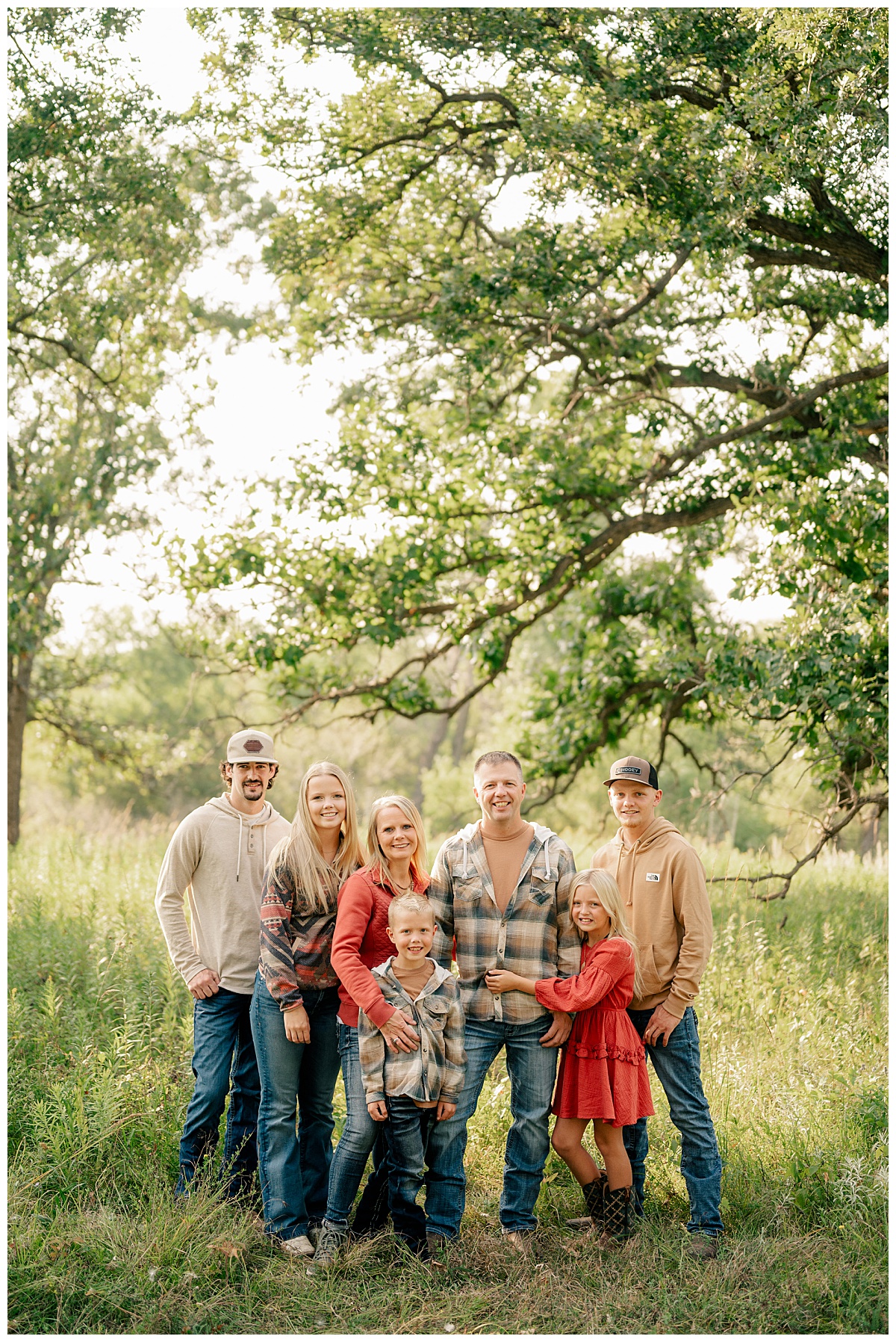 family gathers together in meadow as light hits grasses by Minnesota photographer
