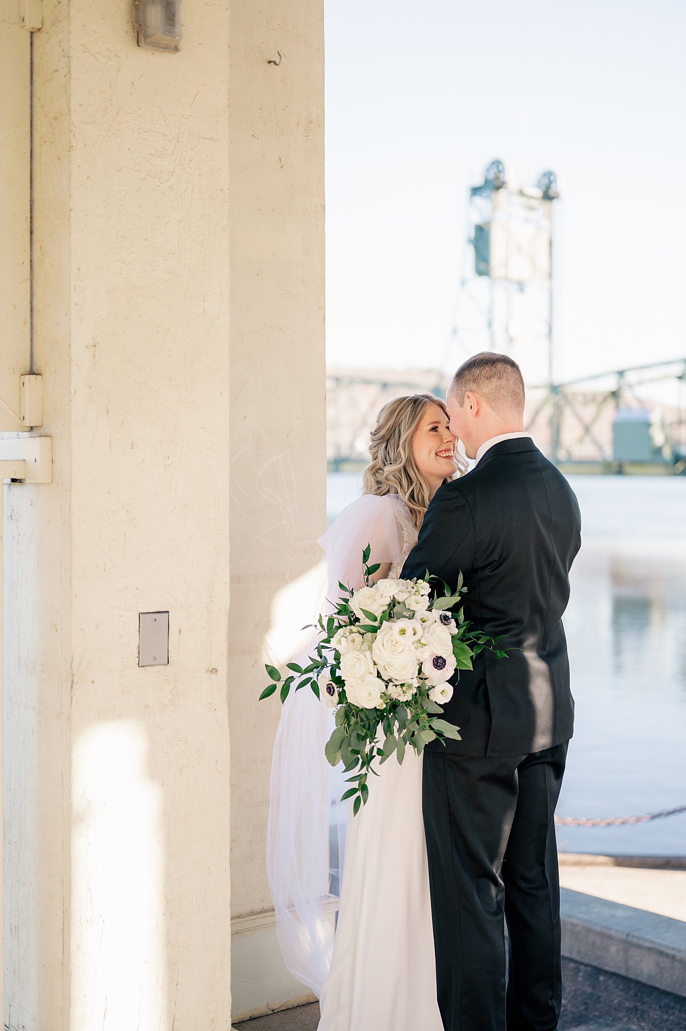 groom touches noses with his bride along the water by Minnesota Wedding Photographer