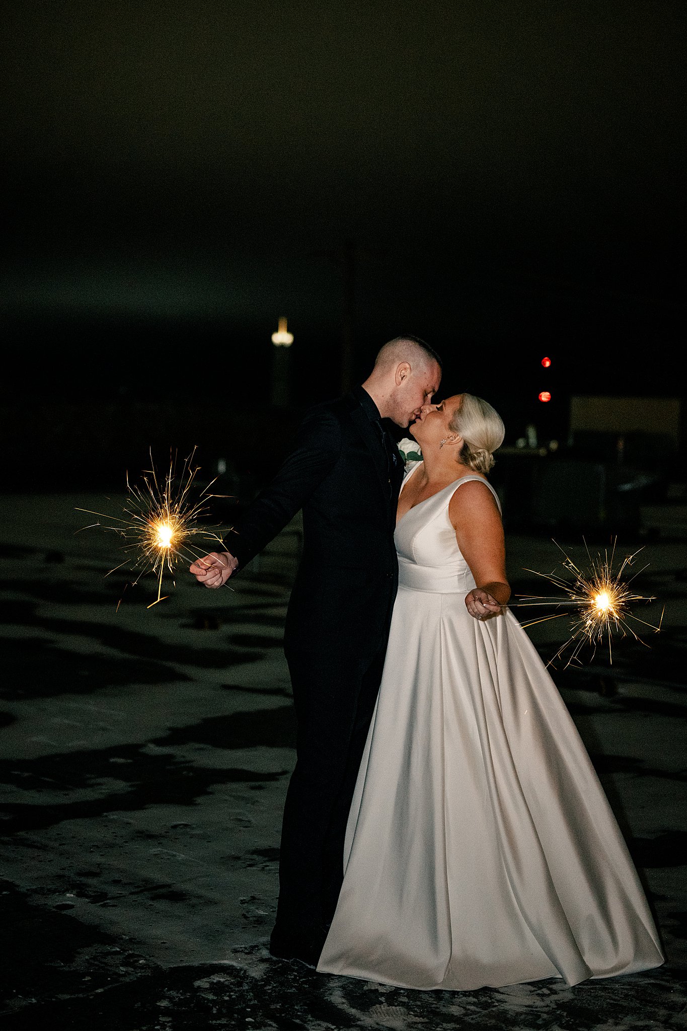 newlyweds hold sparkers as they kiss at night by Minnesota Wedding Photographer