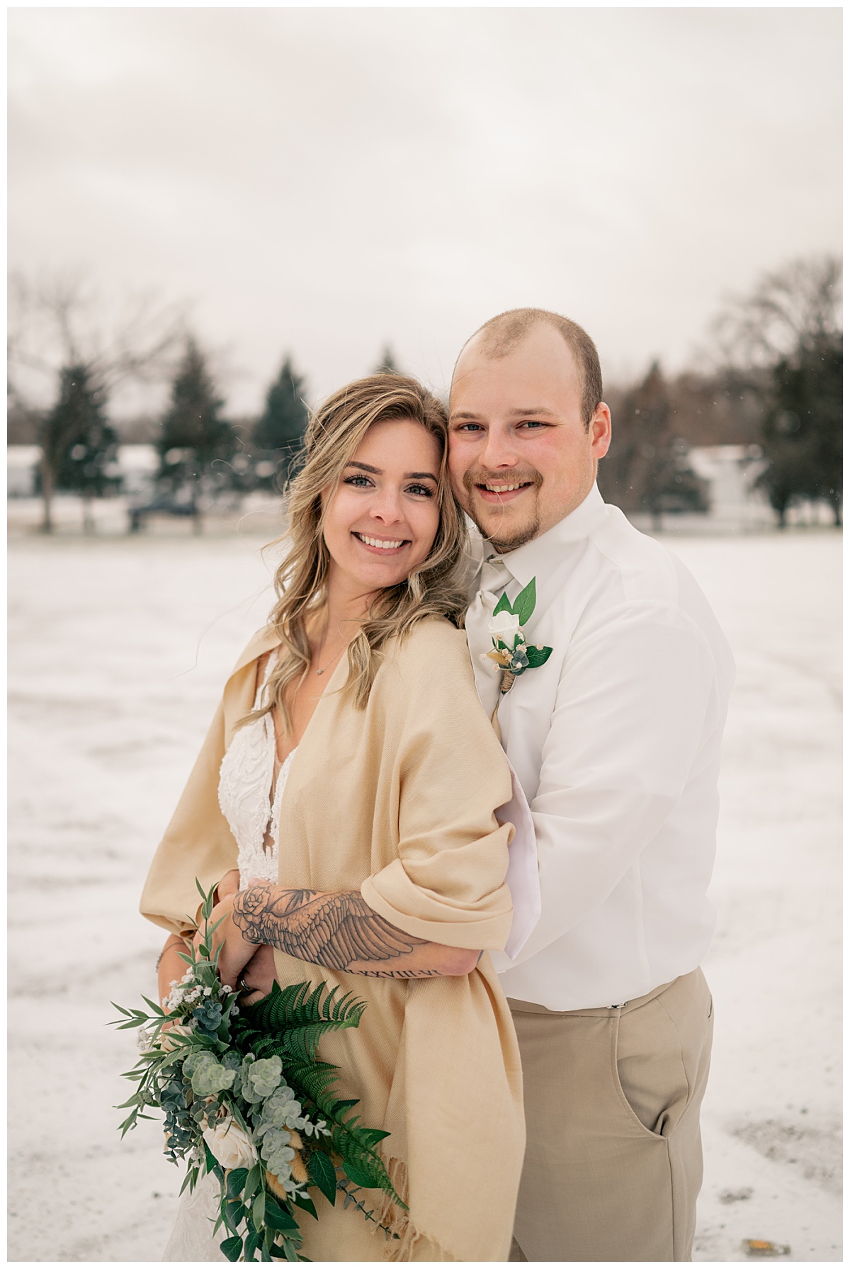 newlyweds smile together in the snow by Minnesota wedding photographer