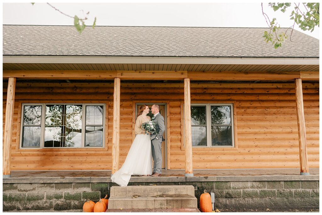 couple looks at each other on steps of log cabin by Minnesota wedding photographer