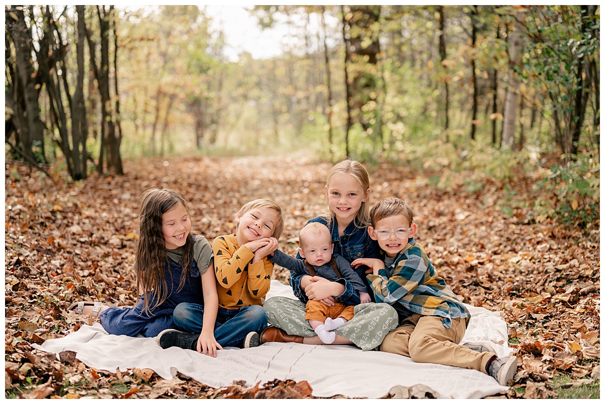 siblings sit on blanket together hugging each other by Minnesota photographer