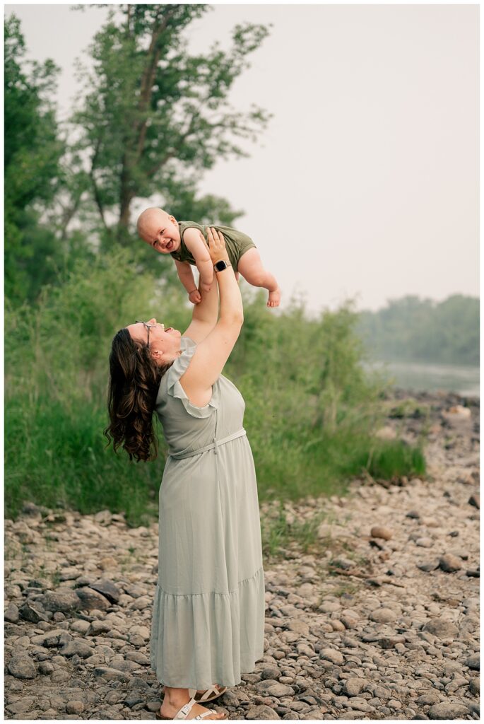 mom lifts her smiling baby up into the air by Minnesota wedding photographer