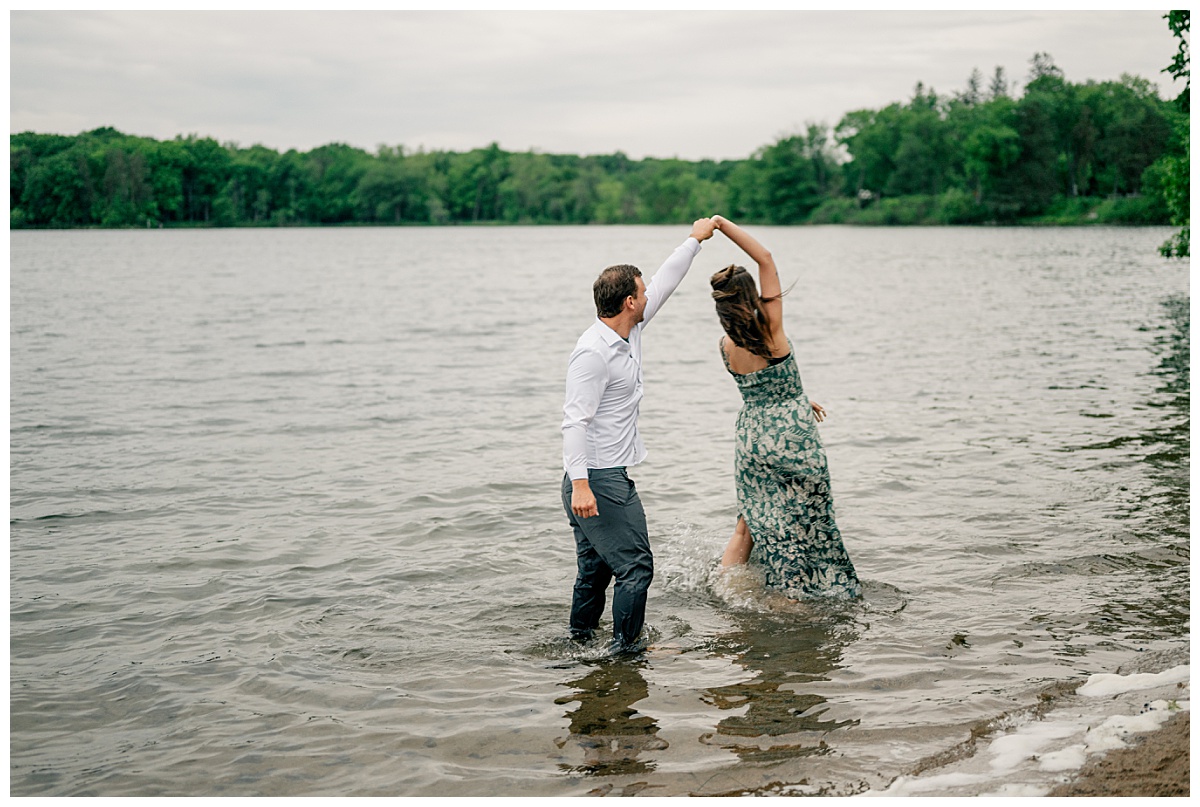 client connections are shown off when man spins woman in shallow water along shore of lake