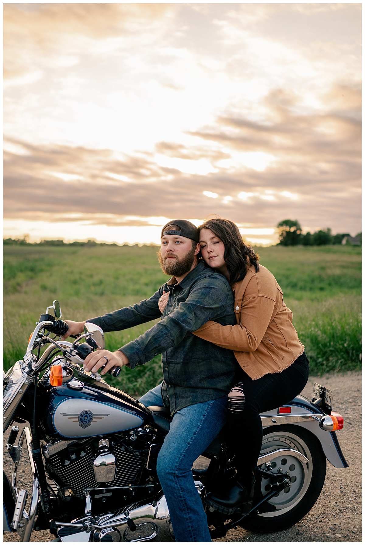 woman wraps arms around man as they ride motorcycle at sunset by Rule Creative Co