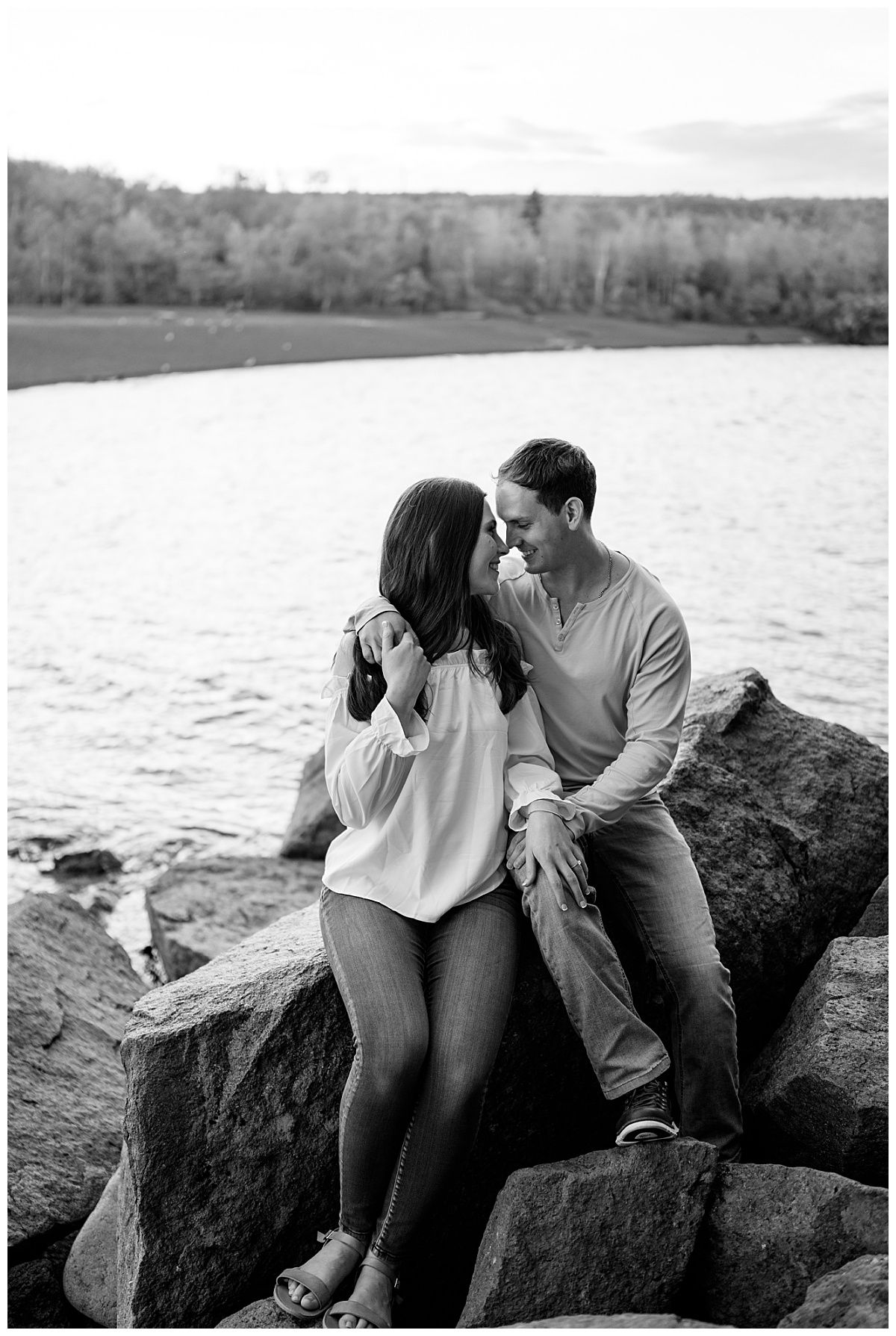 couple sits on rock touching noses and smiling by Minnesota photographer