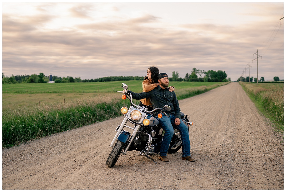 woman leans on a man sitting on motorcycle during editing workflow