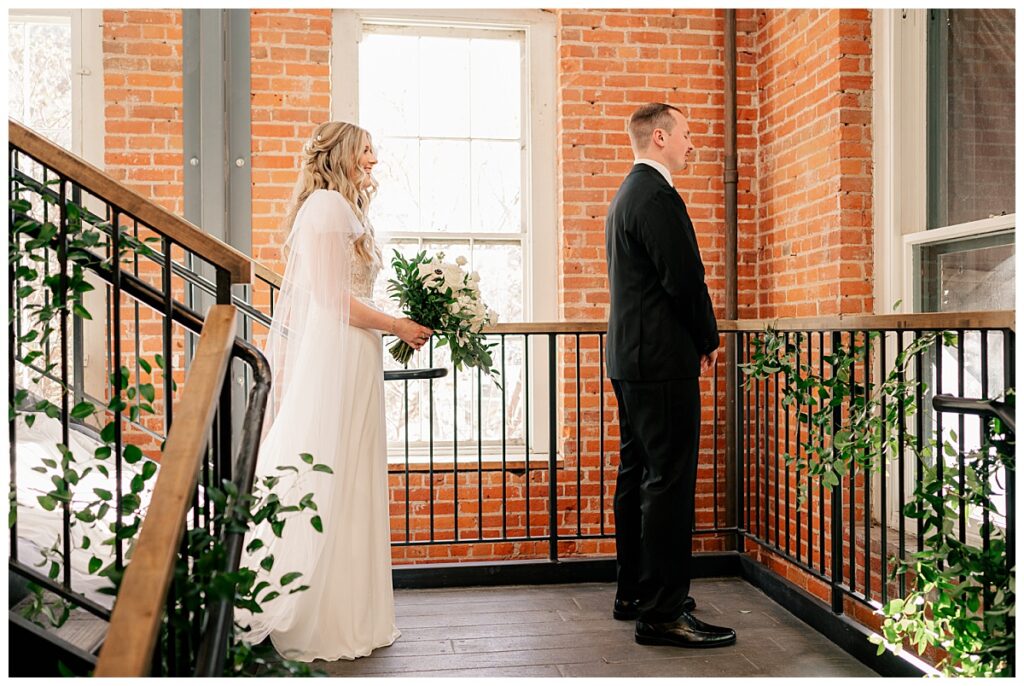 bride waits behind groom before first look 