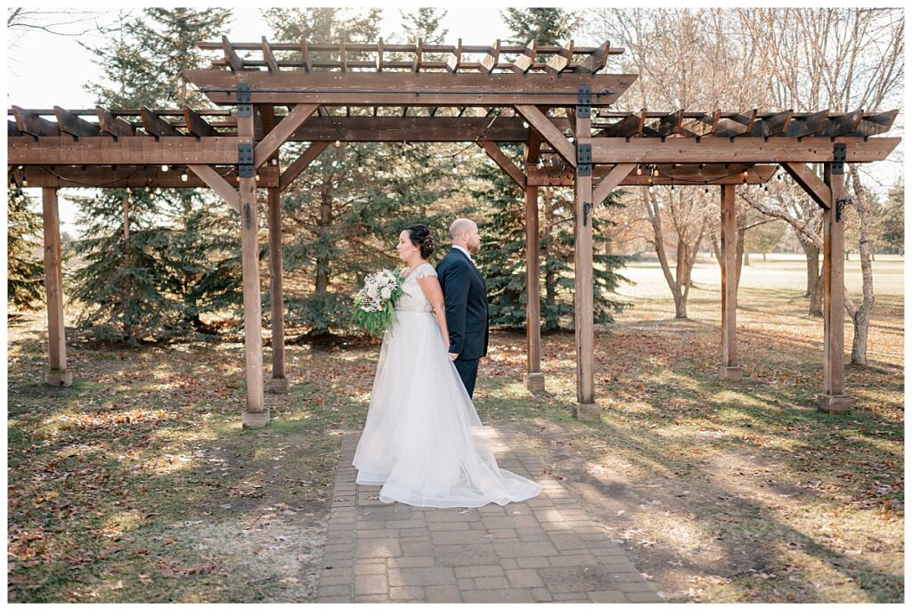 bride and groom stand back to back before first look 