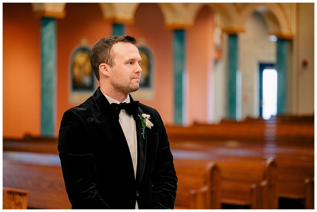 groom looks down aisle waiting for bride by Minnesota wedding photographer