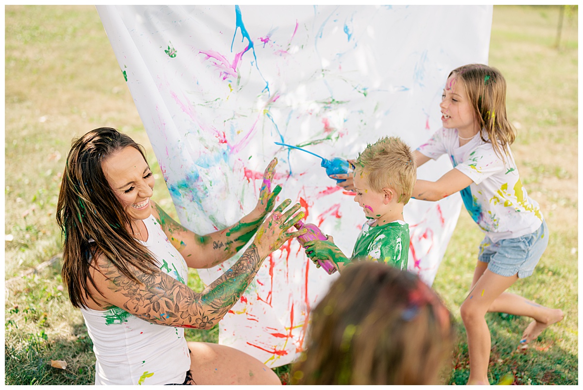 kids throw paint on mom as she laughs by Rule Creative Co