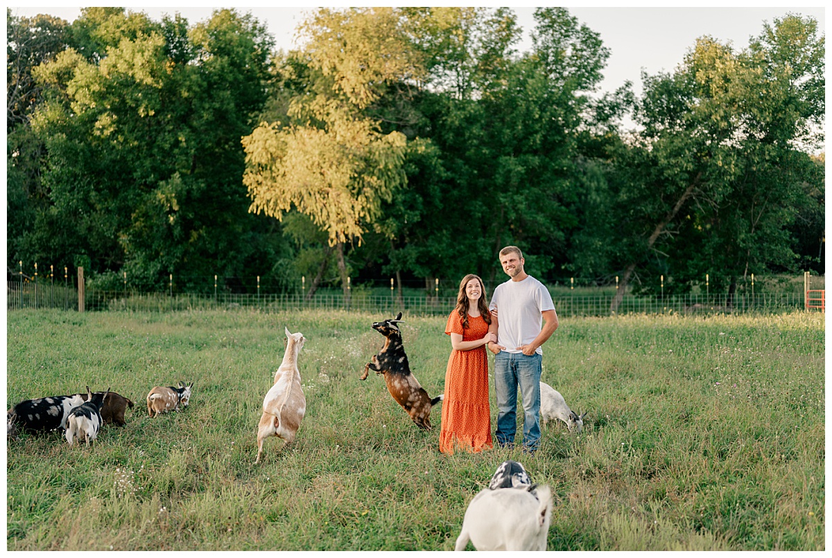 couple stands in field with goats by Rule Creative Co