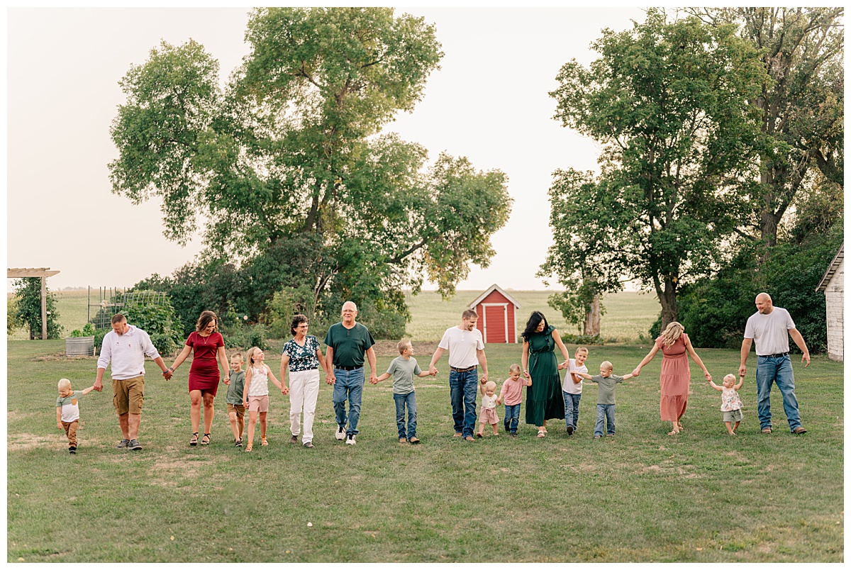 extended family walks holding hands for professional photos