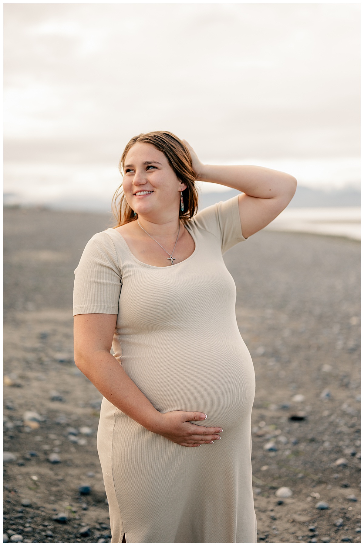 pregnant woman holds growing belly while looking over shoulder by Minnesota photographer