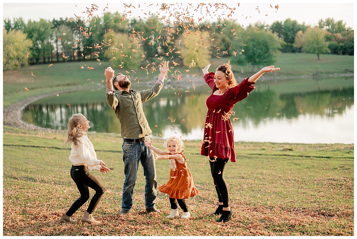 parents and kids throw leaves in the air near a lake by Minnesota photographer