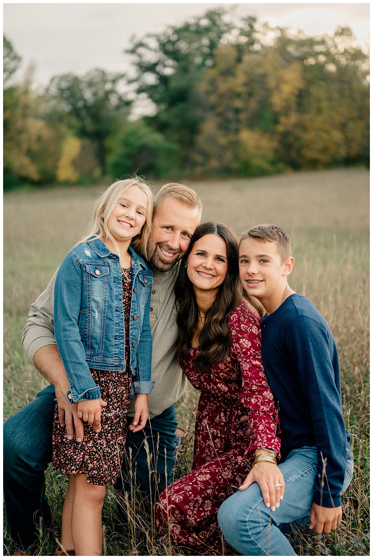 family gathers close and smiles in field by Minnesota photographer
