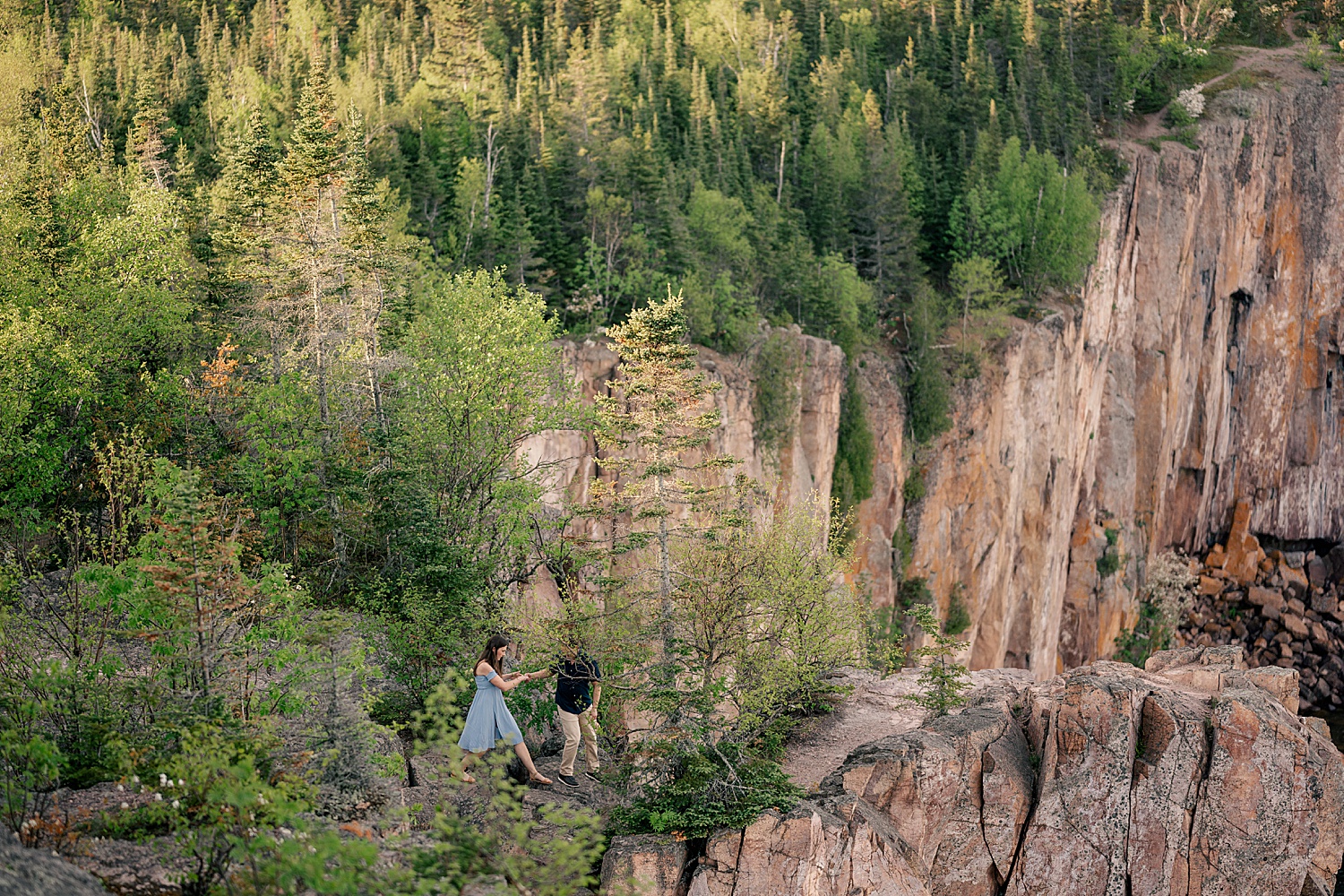 couple in blue walk on the cliffs for golden hour at North Shores