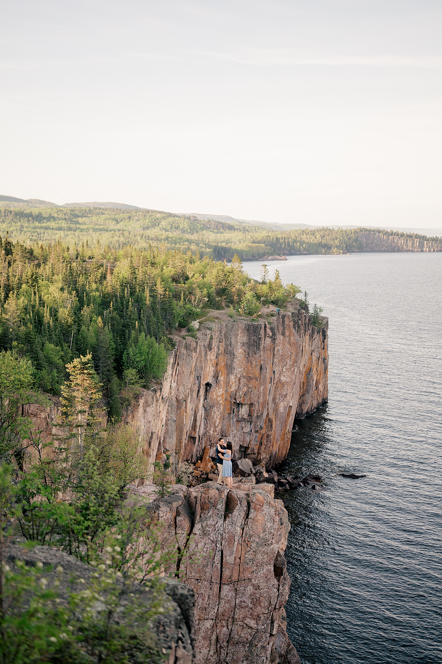 couple hugs on cliffside over Great Lakes by Rule Creative Co