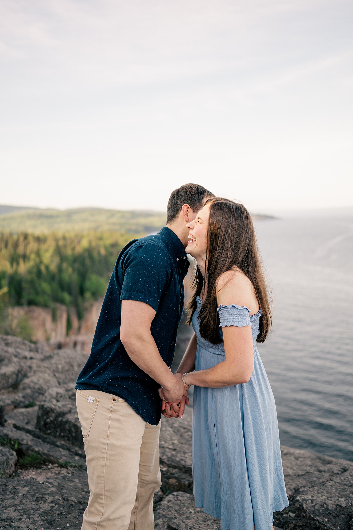 woman giggles as her fiancé whispers in her ear by Minnesota wedding photographer