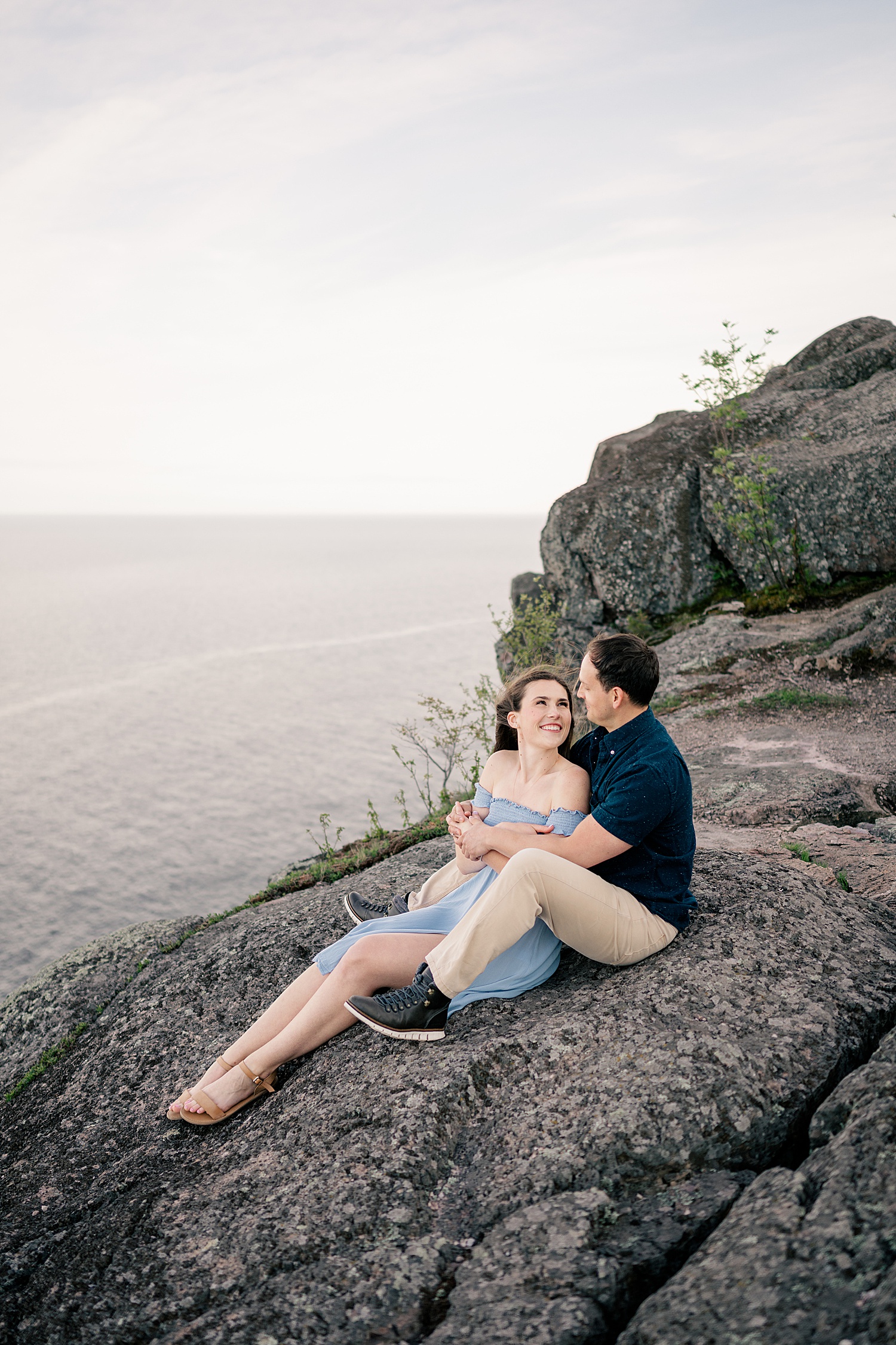 woman and man sit on rock embracing by Rule Creative Co