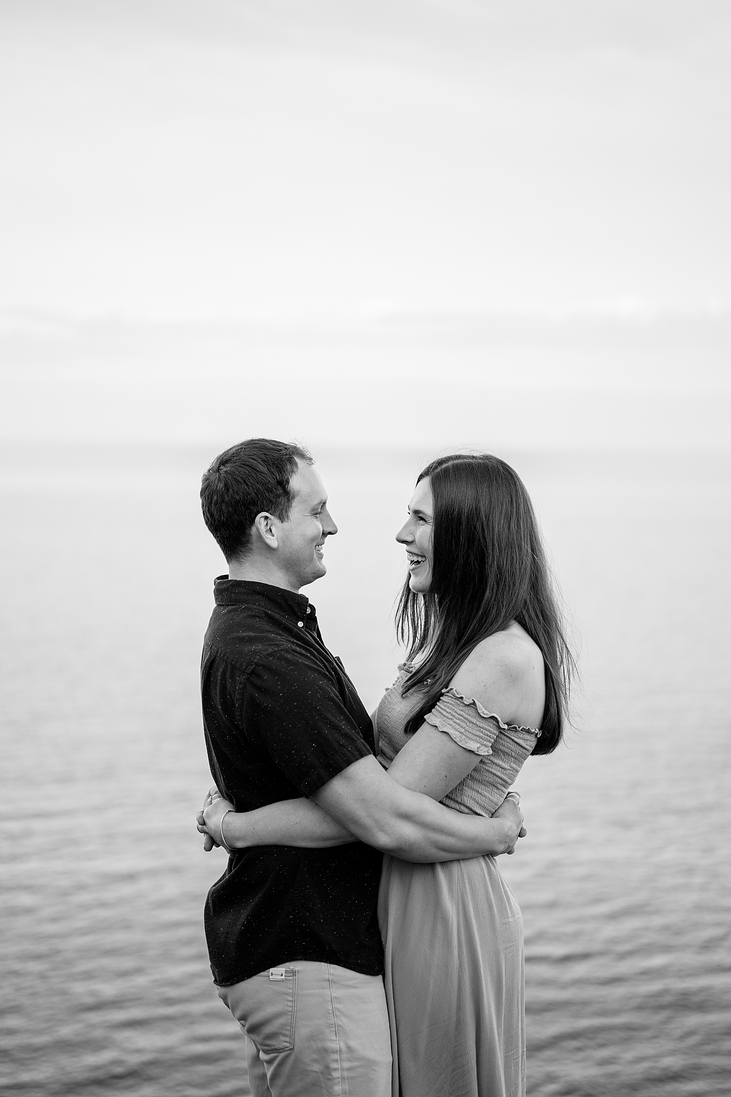 engaged couple hug in front of the Great Lakes by Minnesota wedding photographer