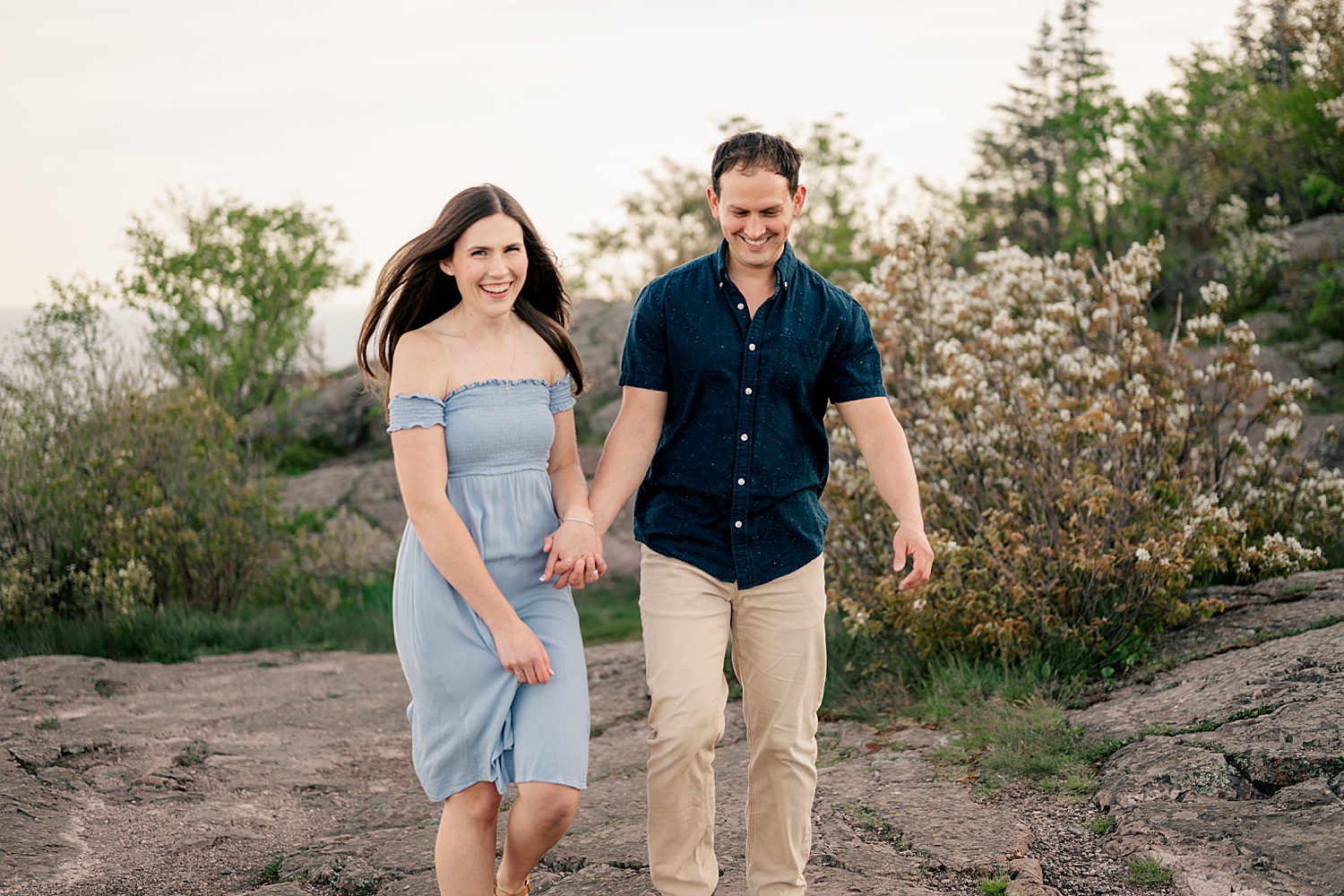 man in blue shirt and woman in dress walk for golden hour at North Shores