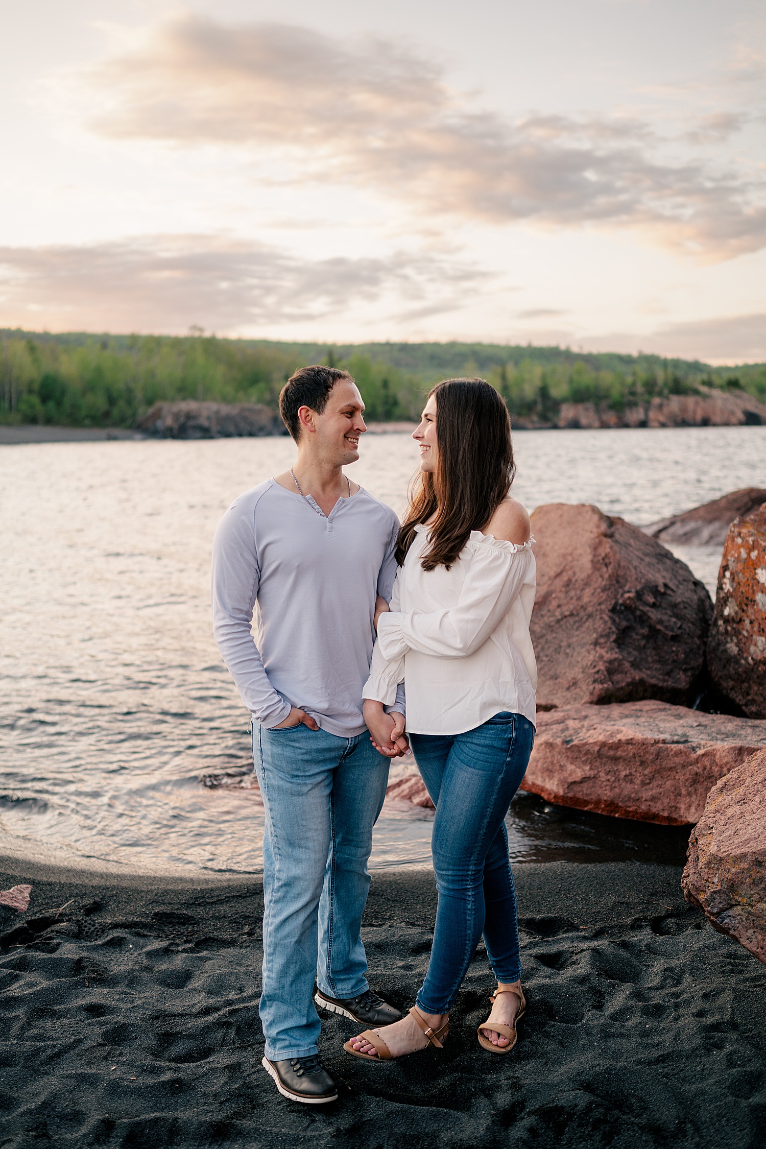 brunette couple hold hands on the beach for golden hour at North Shores