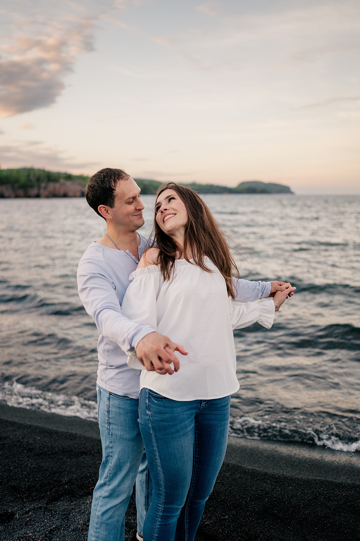 engaged couple dance in front of beach by Minnesota wedding photographer