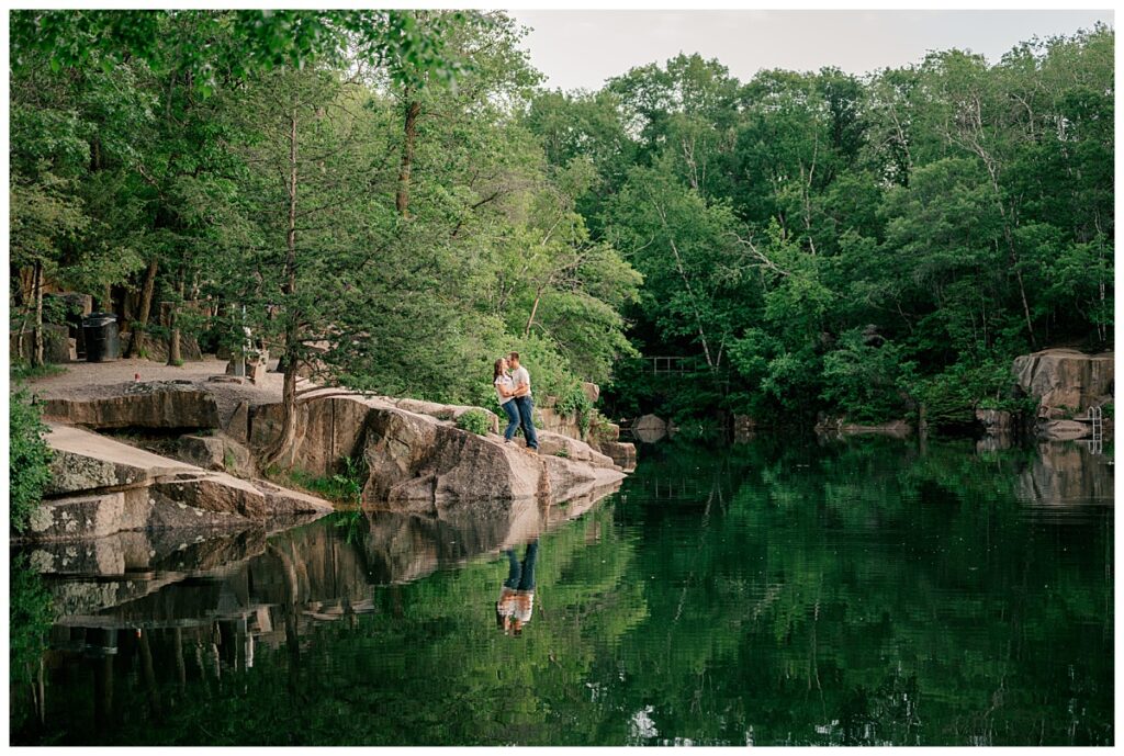 couple stands on rock outcropping leaning in for a kiss at Quarry Park engagement session 