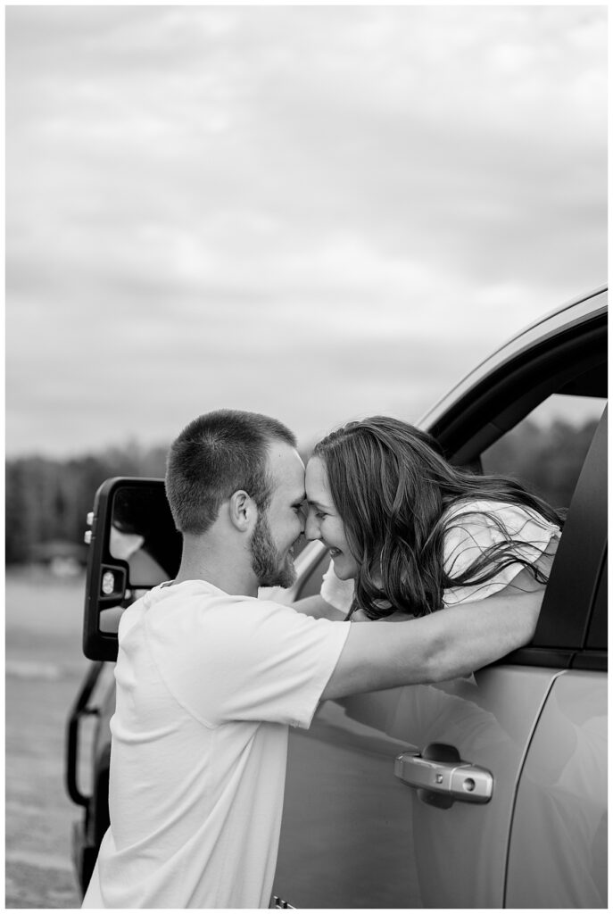 man wraps his arms around his fiance as she leans out the window of a truck by Rule Creative Co