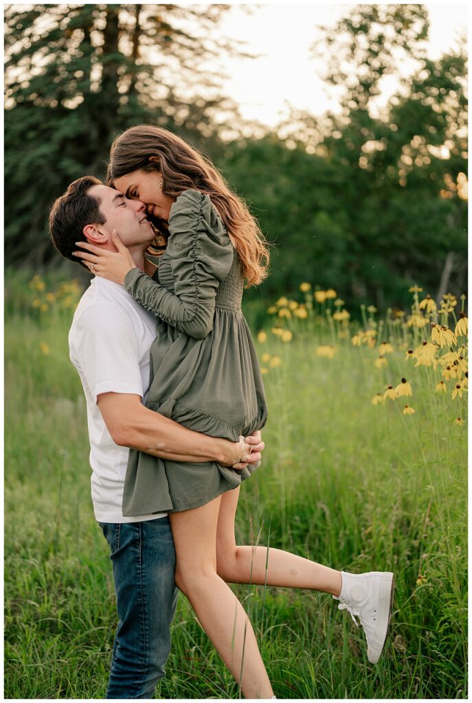 man lifts up woman as she leans to kiss him by Minnesota wedding photographer