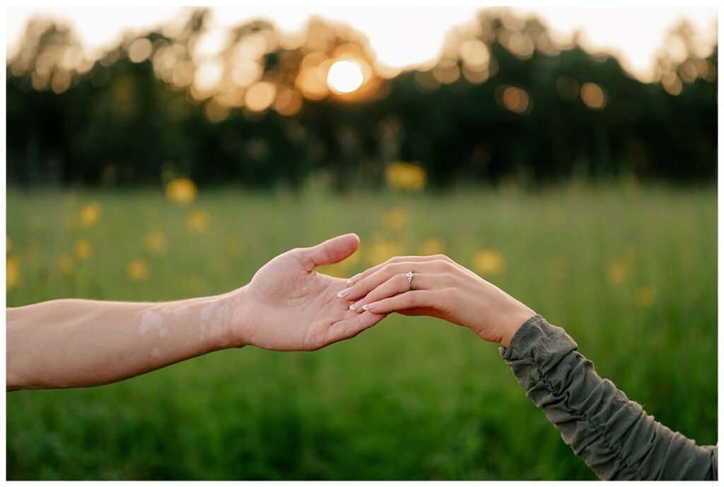 woman places her hand with engagement ring in man's by Minnesota wedding photographer