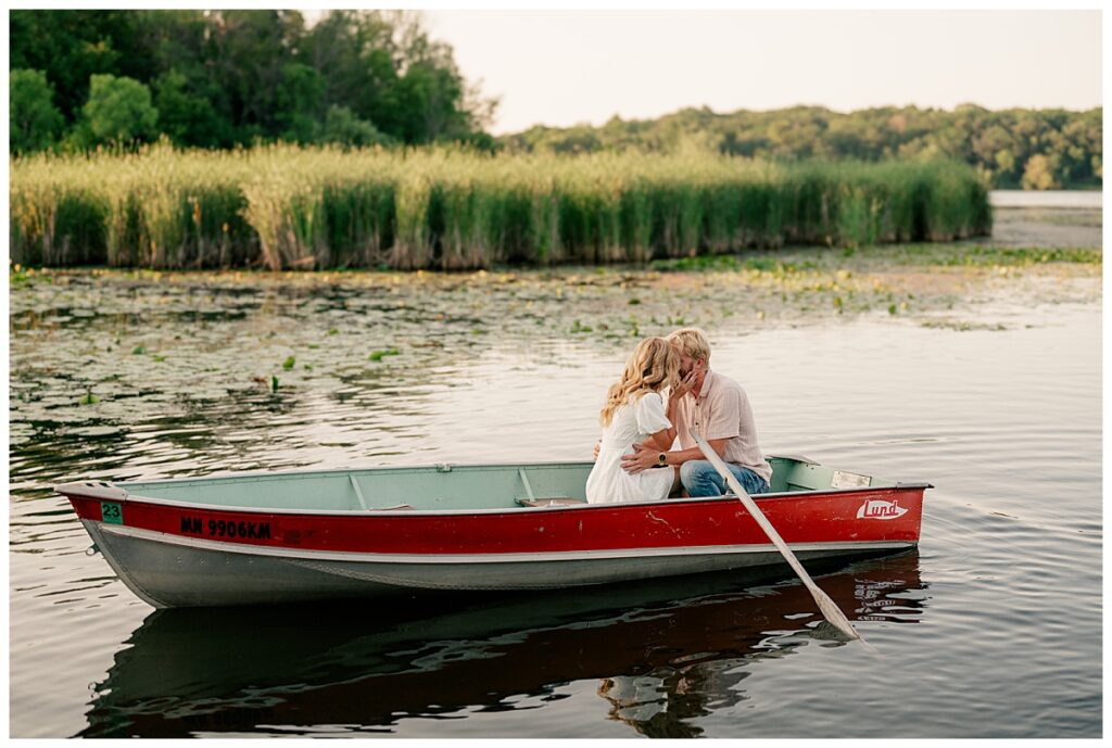 couple kisses in boat on lake at Fish Park engagement session