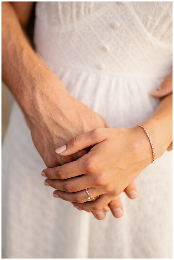 woman rests her hand on fiance's to show off her ring by Rule Creative Co