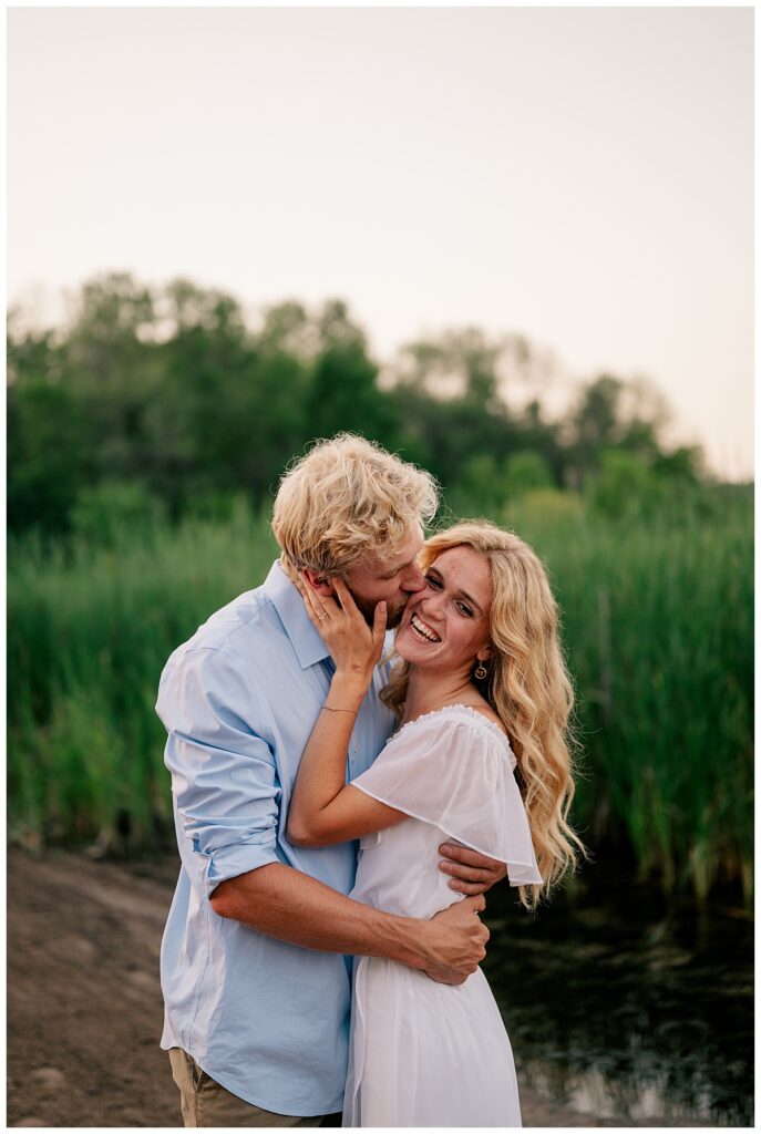 man kisses woman on the cheek as she smiles by Rule Creative Co