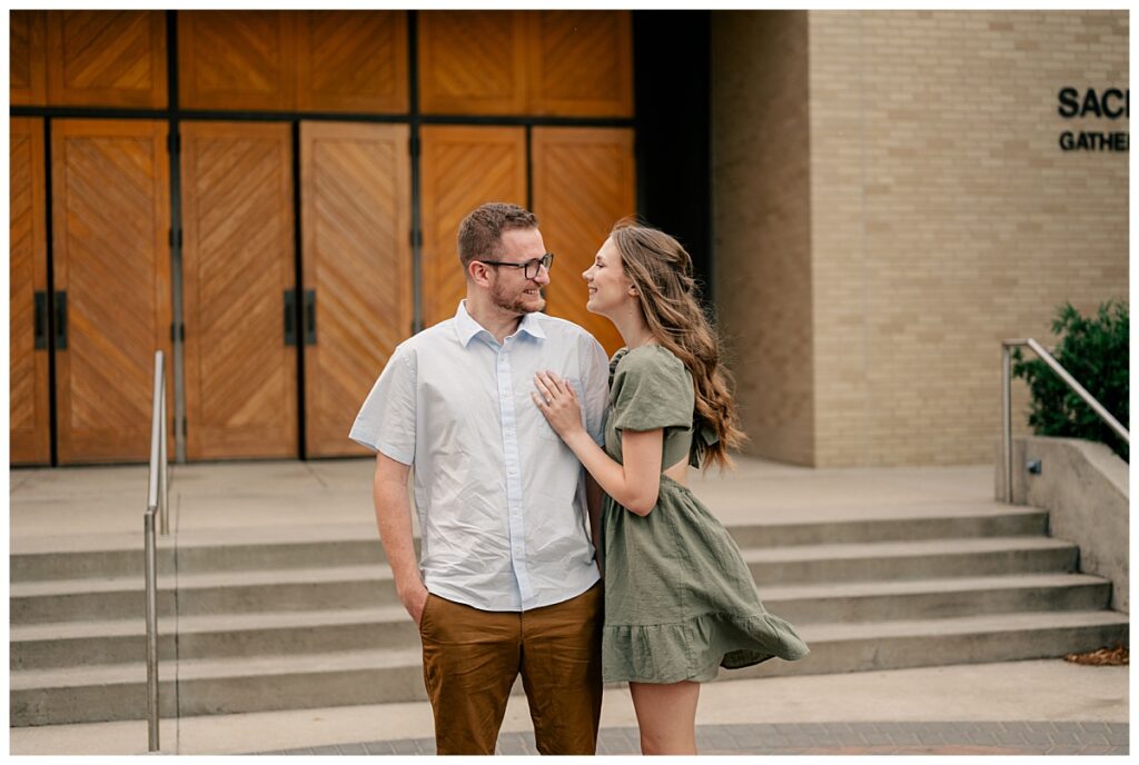 woman rests hand on man's chest as they smile at each other during engagement at St. John's University