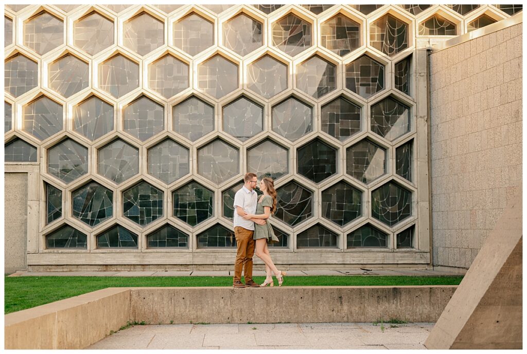 bride to be kisses groom in front of large window by Rule Creative Co