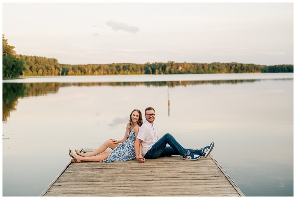 couple sits on dock overlooking lake by Minnesota wedding photographer