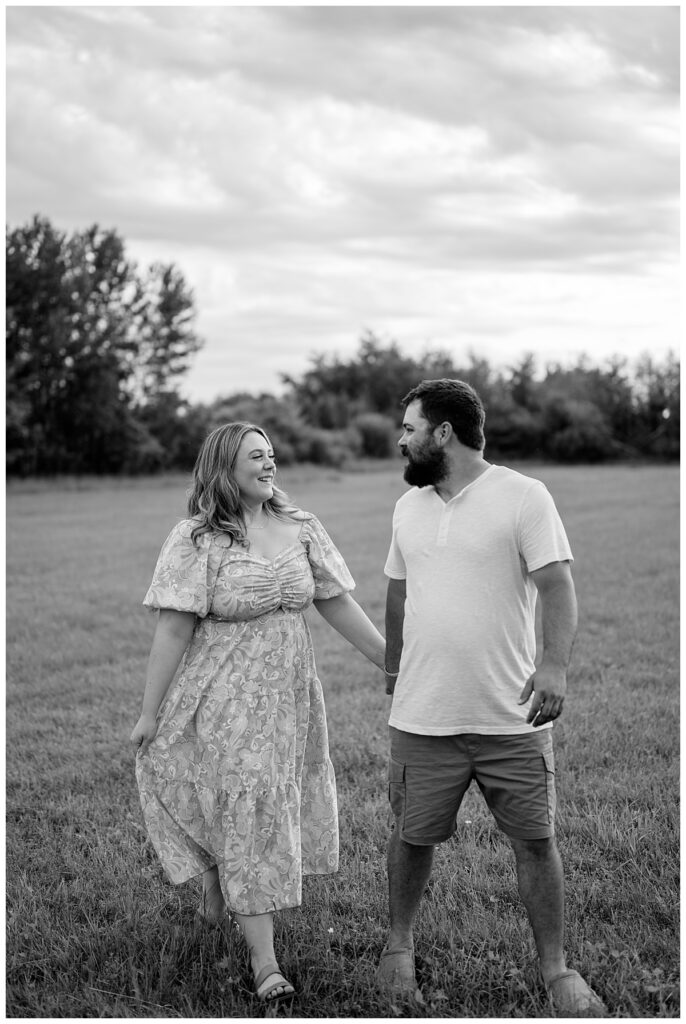 husband and wife hold hands and look at each other as they walk at flower farm couples session