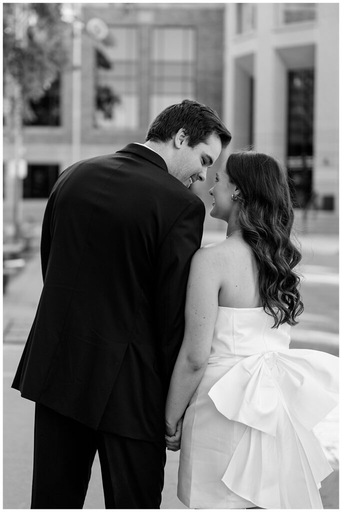 woman in dress with large blow holds hands with man by Minnesota wedding photographer