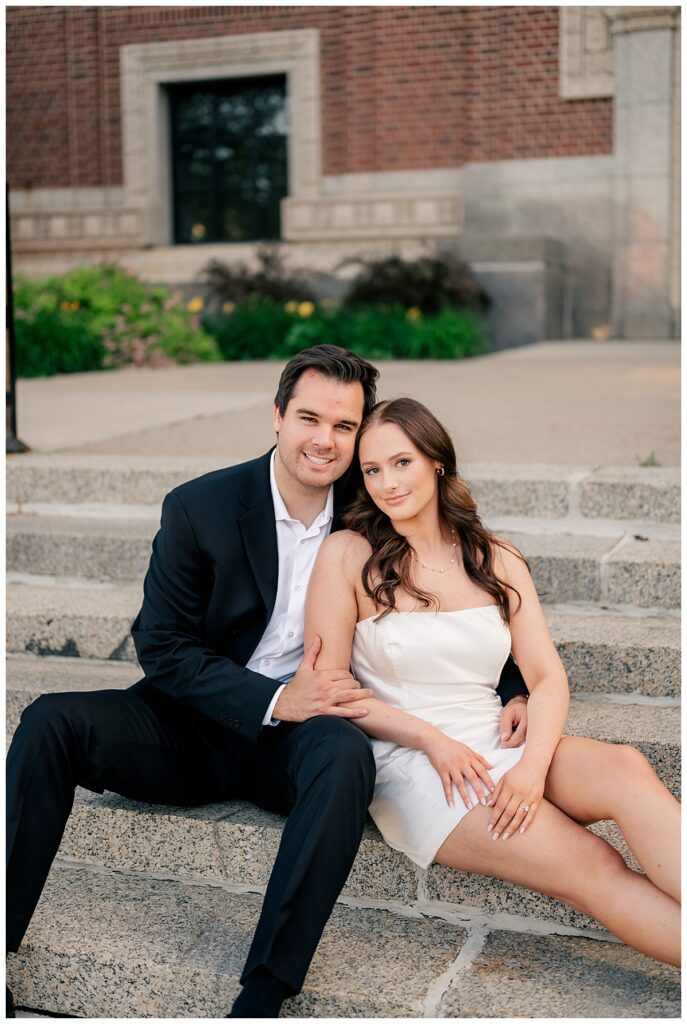 couple sits on steps leaning on each other by Minnesota wedding photographer