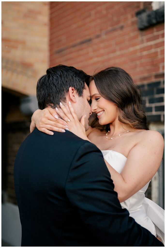 woman wraps arms around man as she touches her forehead against his at Downtown St. Cloud engagement session