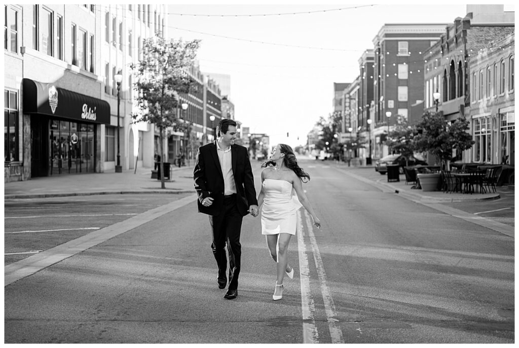 couple walks down road together looking at each other by Minnesota wedding photographer