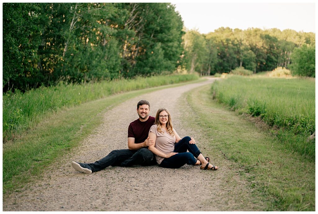 man and woman sit together in path at Quarry Park evening engagement session 