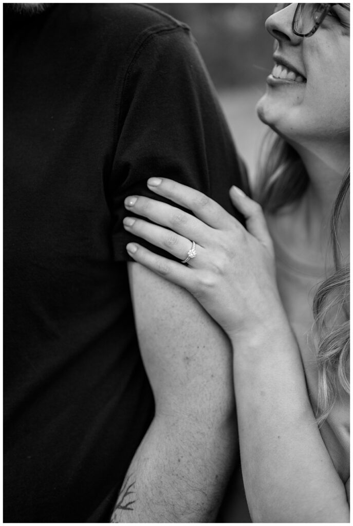 woman places hand on man's arm to show off ring by Minnesota wedding photographer